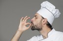 male-chef-white-uniform-making-tasty-sign-against-gray-background.jpg
